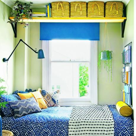 Gult och blått sovrum med mönstrade sängkläder och ett fönster bredvid sängen.