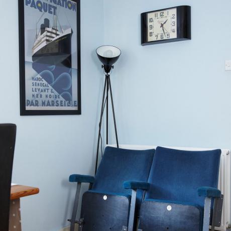 Столове в стил кино срещу боядисани в светло синьо стени с подова лампа и часовник
