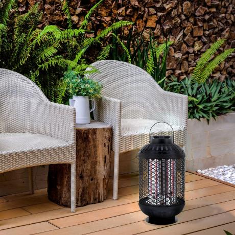 En lille lanterne elektrisk terrassevarmer på gulvet ved to grå rattan udendørs stole