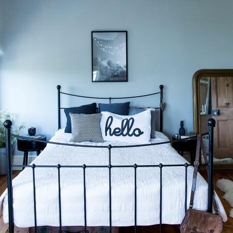 modro šedá spálňa s kovovou čiernou posteľou a čiernymi nočnými stolíkmi