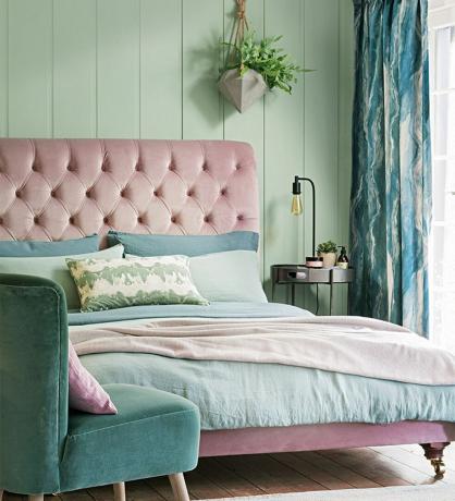 Schlafzimmer mit grün getäfelten Wänden und rosa samtgepolstertem Kopfteil