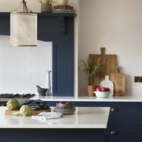 白いタイルのスプラッシュバックと直立した青いキッチン