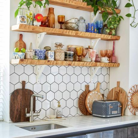 Estantes de cocina abiertos sobre azulejos blancos hexagonales en la cocina