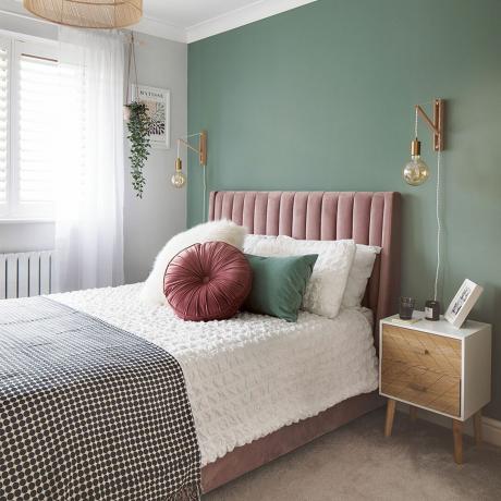 dormitor cu peretele vopsit în verde și pat tapitat din catifea roz