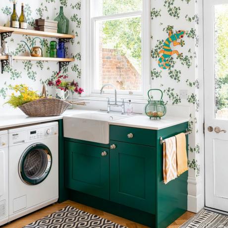 veļas mašīna saimniecības telpā ar botāniskām tapetēm un zaļu skapi