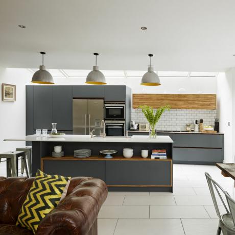 Кухня с отворен план със сиви единици и кожен диван