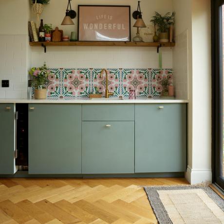 Zelená moderní kuchyně s rohožkou vedle zadních dveří.