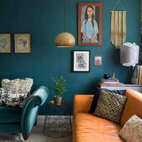 sala de estar verde azulado con sofá de terciopelo verde azulado, sofá de cuero marrón claro y pared de galería con obras de arte y tapices