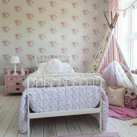 Dormitorio para niños con marco de cama de metal con papel tapiz rosa y tippee
