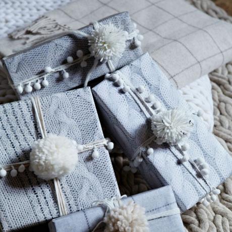 подаръци, опаковани в плетена фотографска подаръчна опаковка с плетени помпони декорации