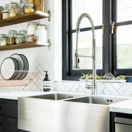 moderna crna kuhinja s bijelim pločicama i površinama te sudoperom od nehrđajućeg čelika
