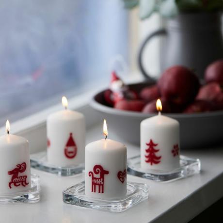 IKEAs Vinterfint vita blockljus med röda julmotiv på en fönsterbräda