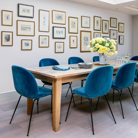 Sala da pranzo bianca con sedie blu e parete con foto
