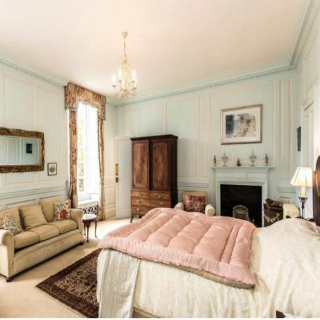 غرفة نوم مع سرير أبيض وأريكة وسجاد بيج وألواح زرقاء وخزانة ملابس بنية