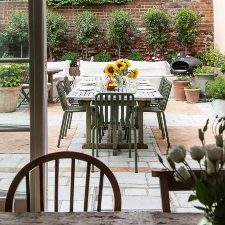 изглед от трапезарията към павирана градина за хранене и кът за сядане