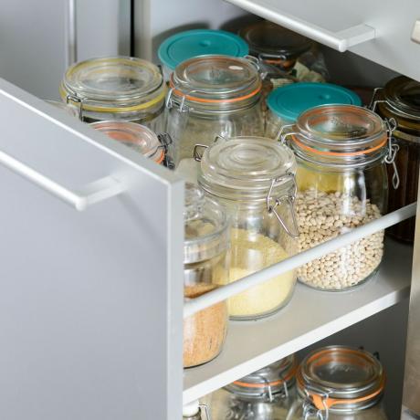 Gaveta aberta mostrando alimentos armazenados em potes de vidro transparente