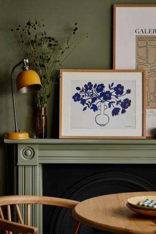 obras de arte florales en azul sobre un fondo blanco en un marco de madera sentado en un manto al lado de una lámpara amarilla