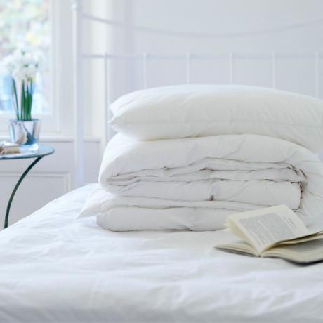 Kasa peittoja taitettuna peittämättömälle sängylle