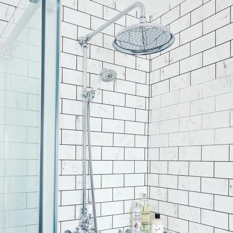 Głowica prysznicowa w białej łazience z ekranem prysznicowym