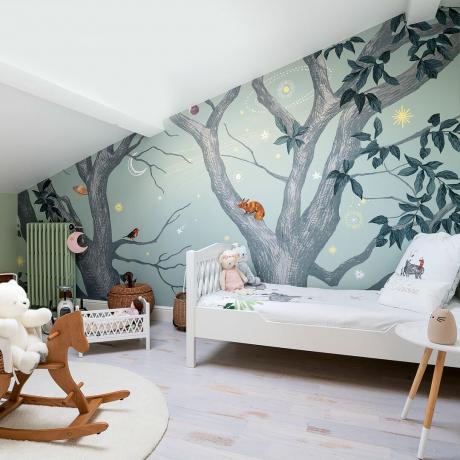 Bēniņu guļamistabas bērnistaba ar meža sienas gleznojumu un šūpuļzirdziņu
