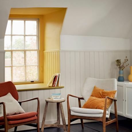 spațiu de locuit alb cu două fotolii, masă și zonă de fereastră galbenă