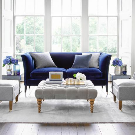 Bela in siva dnevna soba z mornarsko modrim kavčem