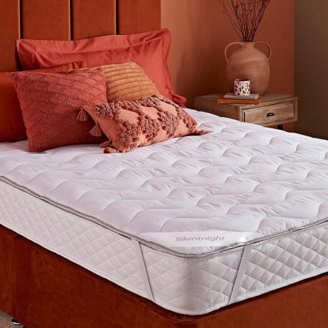 rdzawe wezgłowie i podstawa łóżka z białym materacem i nakładką
