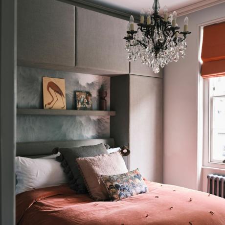 ダークピンクの寝具セット、ベッドの上に装飾的なクッション、ヘッドボードの上の棚、黒いシャンデリア