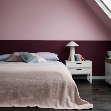 sypialnia na poddaszu z dwukolorowymi różowymi ścianami i białymi meblami