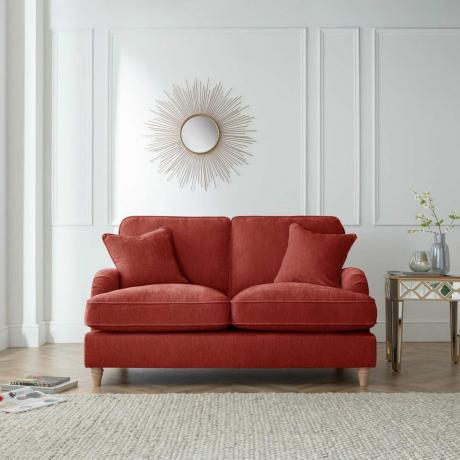 Abrikosų spalvos sofa neutraliame kambaryje