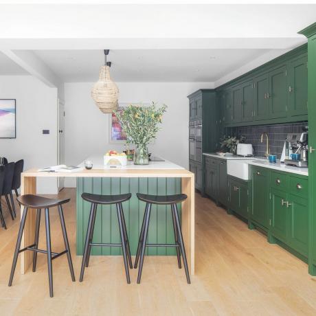 Cucina abitabile con grande isola verde, piano colazione in legno e unità verdi
