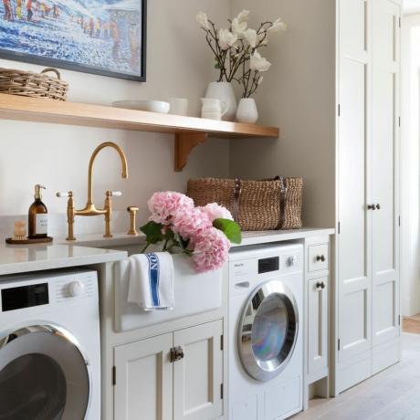 Hvitt kjøkken med tredetaljer og montert vaskemaskin