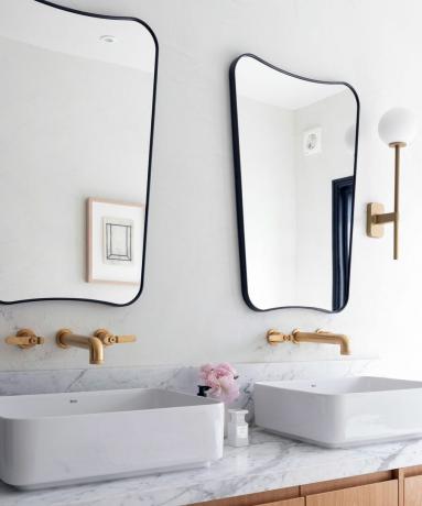 שתי מראות קיר שחורות תלויות מעל כיורים לבנים כפולים בחדר האמבטיה
