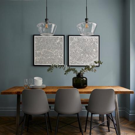 zila ēdamistaba ar koka galdiem un pelēkiem krēsliem un izdrukām uz sienas