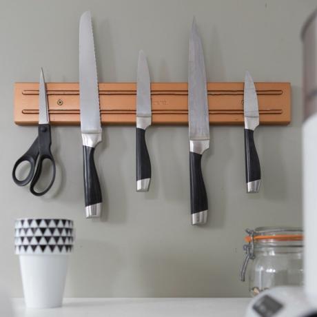 Bližnji posnetek kuhinjskih nožev na magnetu za nože