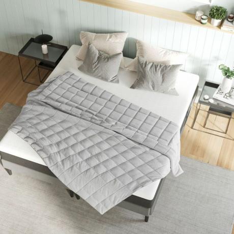 سرير أبيض في غرفة النوم مع بطانية مرجحة رمادية