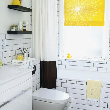 Baltas vonios kambarys su metro plytelėmis ir geltona žaliuze
