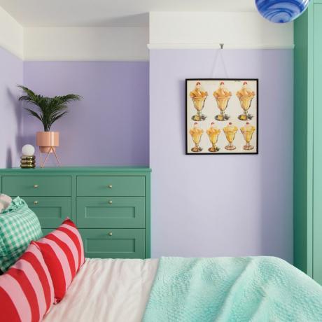 Lila Schlafzimmer mit grünen Möbeln und gemusterten Kissen