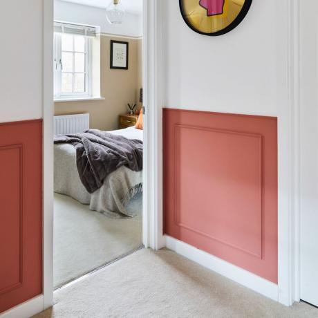 Двухцветные стены с эффектом лепнины из белых и красных панелей, смотрящих в дверной проем спальни