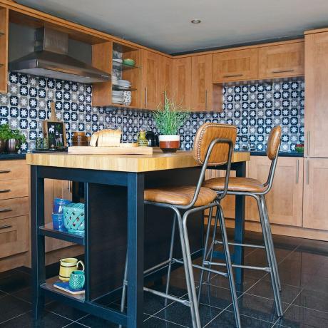 Cocina con gabinetes de madera, calcomanías de azulejos, isla de cocina azul marino con taburetes de cuero