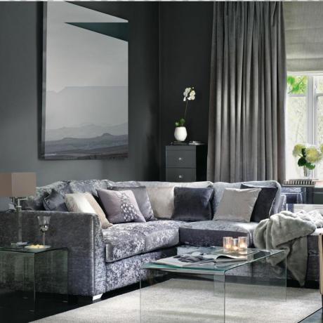 Modernes graues Wohnzimmer mit L-förmigem Sofa aus grauem Pannesamt und minimalistischem Couchtisch aus Glas auf cremefarbenem Teppich.