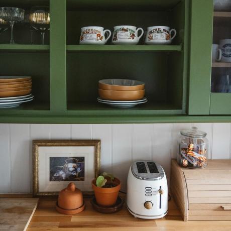 Roheline köök avatud riiulite ja puidust lettidega.