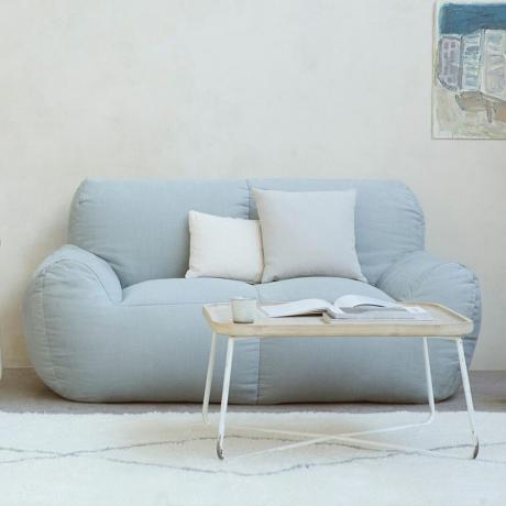 Šviesiai mėlyna sofa su rašomuoju stalu priešais