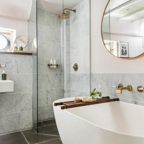 Bledoružová kúpeľňa so sivou mramorovou dlažbou a mosadznými batériami a sprchovou hlavicou