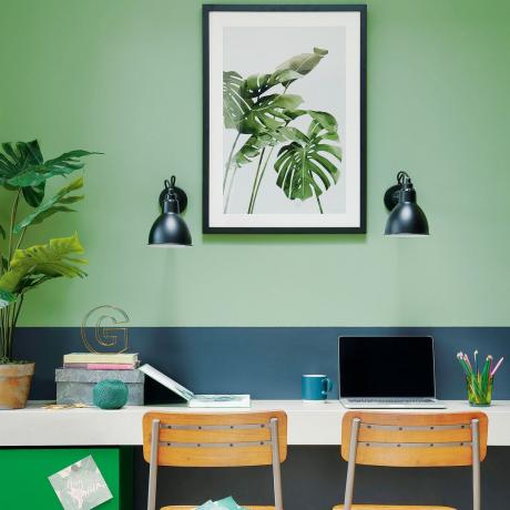 Žalias namų biuras su rudomis kėdėmis ir sieniniais šviestuvais