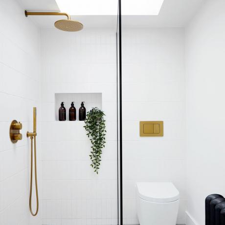 Baltas dušo kambarys su stoglangiu ir žalvario detalėmis