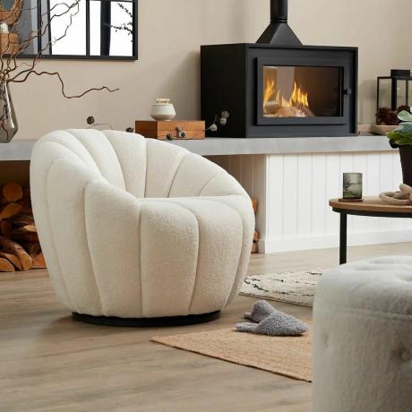 Boucle křeslo Homebase v obývacím pokoji s krbem na dřevo, dřevěnými podlahami a dalším nábytkem