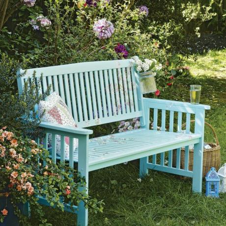 芝生の上に青緑色に塗られた庭のベンチ