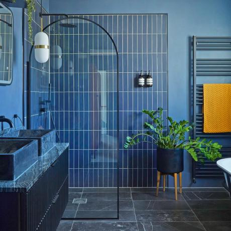 Mėlynos plytelės mėlyname vonios kambaryje su dušo sienele