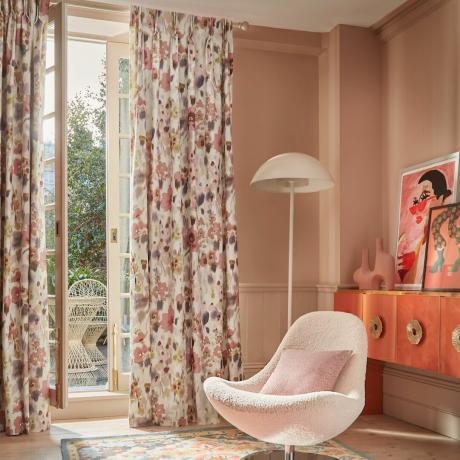 Rózsaszín szoba fehér székkel, lámpával és virágfüggönyökkel